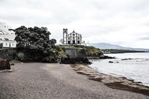 a house on a hill next to the ocean at Casa a 2 minutos a pé de piscina natural in Ponta Delgada