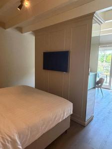 a bedroom with a bed and a tv on the wall at Maison Cromvoirt in Cromvoirt