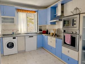a kitchen with blue cabinets and a washing machine at Chalet Amarena 20812 in Argoños