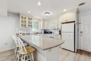a kitchen with white cabinets and a white refrigerator at Long Sands Escape in York