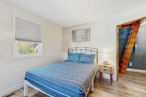 a bedroom with a bed with a blue comforter and two windows at Long Sands Escape in York