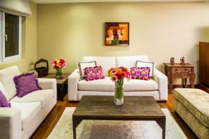 una sala de estar con sofás y un jarrón de flores sobre una mesa en Apart-Hotel Casa Serena, en Guatemala