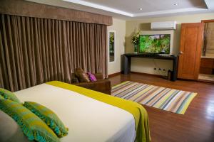 a hotel room with a bed and a flat screen tv at Apart-Hotel Casa Serena in Guatemala