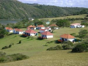 a group of houses in a field with a river at Igoda Mouth Resort in Winterstrand