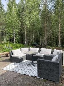 a patio with couches and a table and trees at Koivuniemen Ranch in Hämeenlinna