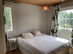 a bedroom with a bed and two windows at Koivuniemen Ranch in Hämeenlinna