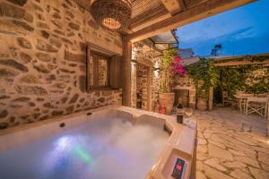 an outdoor bath tub in a room with a stone wall at Boutique Cretan house in Old Malia with Jacuzzi in Malia