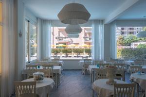 a restaurant with white tables and chairs and windows at Hotel Riviera in Deiva Marina