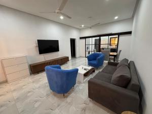 a living room with a couch and blue chairs at Central Residence & Conciergerie Ouaga 2000 in Ouagadougou