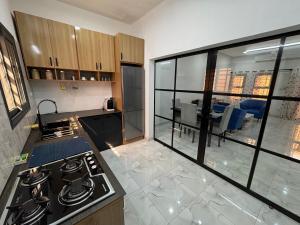 a kitchen with a stove and a view of a living room at Central Residence & Conciergerie Ouaga 2000 in Ouagadougou