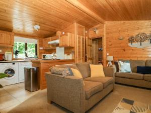 a living room with a couch and a kitchen at Derwent Lodge in Keswick
