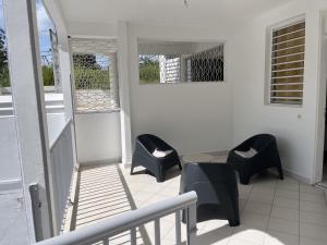 a balcony with chairs and a table and a staircase at Bas de villa 3 chambres - Jardin privé - 20 minutes aéroport in Baie-Mahault