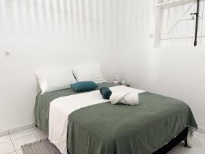 a bed with green and white sheets and a window at Bas de villa 3 chambres - Jardin privé - 20 minutes aéroport in Baie-Mahault