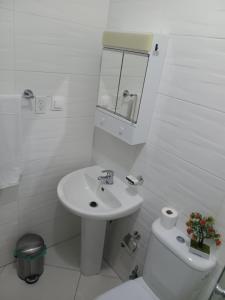 a white bathroom with a sink and a toilet at Selma Space in São Filipe