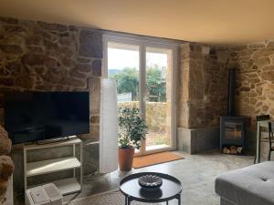a living room with a tv and a large window at Casa dos Carballos in Covelo