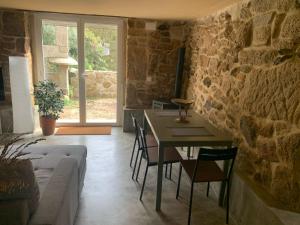a living room with a table and chairs and a stone wall at Casa dos Carballos in Covelo