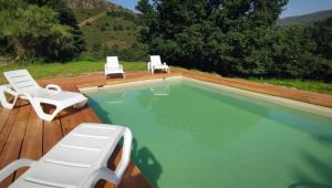 a swimming pool with two lawn chairs and two lounge chairs at Casa dos Carballos in Covelo