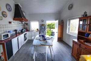 a kitchen with a table and some chairs in it at Quinta do Norte - Biscoitos in Biscoitos +31 photos
