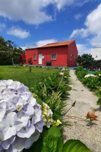 a red house with flowers in front of it at Quinta do Norte - Biscoitos in Biscoitos