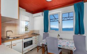 a kitchen with a table and some windows and a table and chairs at Miljak in Duće