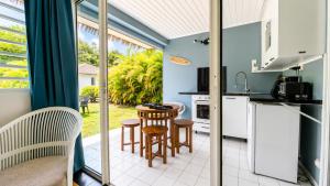 a kitchen with a table and chairs and a window at L'Ecrin d'Oliv - Jardin, Accès plage, Calme assuré in Grand-Bourg