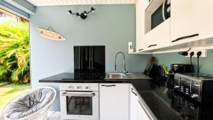 a kitchen with white cabinets and a sink at L'Ecrin d'Oliv - Jardin, Accès plage, Calme assuré in Grand-Bourg