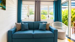 a blue couch in a living room with windows at L'Ecrin d'Oliv - Jardin, Accès plage, Calme assuré in Grand-Bourg
