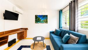 a living room with a blue couch and a tv at L'Ecrin d'Oliv - Jardin, Accès plage, Calme assuré in Grand-Bourg +7 photos