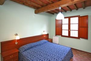 Un dormitorio con una cama azul y dos ventanas. en Tuscany Country Apartments, en Gambassi Terme