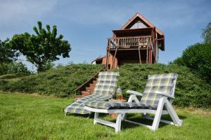 two chairs and a table in the grass with a house at Pajkos Présház in Bakonycsernye