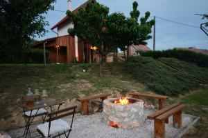 a fire pit with a table and benches in a yard at Pajkos Présház in Bakonycsernye