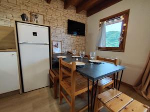 a dining room with a table and a refrigerator at L'Esprit Chalet in Ustou