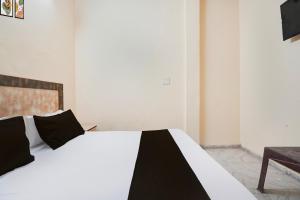 a white bed with black pillows in a room at Hotel O Sector 12 Ghaziabad Formerly VIP Inn in Ghaziabad