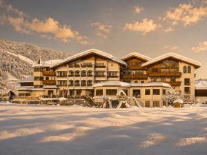 a large lodge in the snow with snow covered ground at Hotel Das Urbisgut in Altenmarkt im Pongau