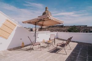 a patio with a table and chairs and an umbrella at La Dimora del Vicolo - Apartment in Francavilla Fontana