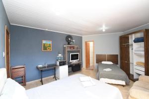 a room with two beds and a desk in it at Suite/loft Jardim Botanico in Curitiba