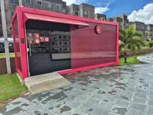 a red building with a bench in a city at Em condominio in Parnamirim