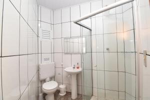 a white bathroom with a toilet and a sink at Suite/loft Jardim Botanico in Curitiba