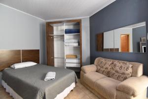 a bedroom with a bed and a couch and a mirror at Suite/loft Jardim Botanico in Curitiba