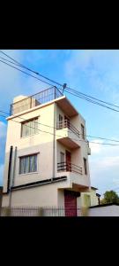 a tall white building with a balcony on it at ML 12 HomeStay in Jakrem