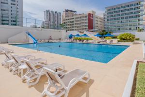 a swimming pool with white lounge chairs and a pool at Ocean View Condo with Resort Amenities in Acapulco