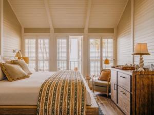 a bedroom with a bed and a chair and windows at Soho Beach House Canouan in Canouan