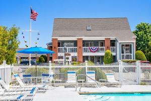 a building with a white fence with chairs and a pool at Elmwood Resort Hotel in Wells