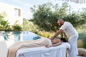 a man is baptizing a woman on a bed next to a pool at Lithos Art Villas - Armonia in Lakíthra