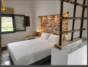 a bedroom with a bed and a brick wall at Olea Heaven Aliveri in Aliveri