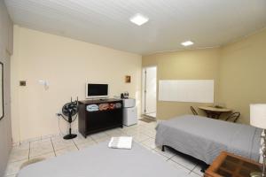 a living room with a bed and a tv at Loft Jardim Botânico 2 in Curitiba