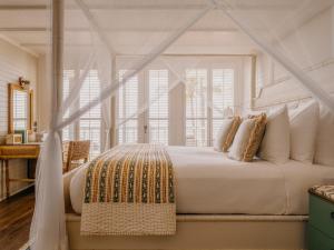 a bedroom with a white bed with a canopy at Soho Beach House Canouan in Canouan