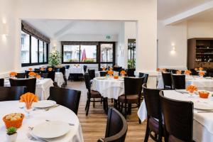 a restaurant with white tables and black chairs at Hôtel Hélianthe in Lourdes