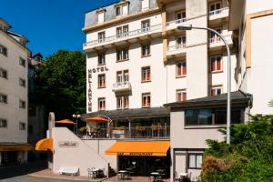 a large white building with tables and chairs in front of it at Hôtel Hélianthe in Lourdes