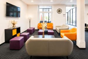 a living room with orange and purple furniture at Hôtel Hélianthe in Lourdes